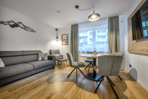 Wohnbereich der Ferienwohnung Daheim in Gastein mit Sofa, Sessel, Essbereich, Smart TV und moderner Alpendekoration