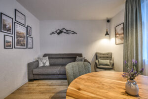 Wohn- und Eßbereich der Ferienwohnung Daheim in Gastein mit Sofa, Sessel und moderner Alpendeko
